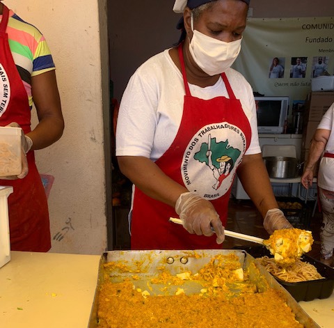 Voluntária servindo refeições no projeto Cozinha Solidária do São Marcos  